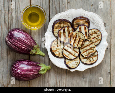 Gegrillte Auberginen gewürzt mit Olivenöl auf einem Holztisch Stockfoto