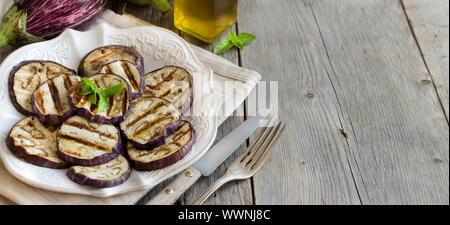 Gegrillte Auberginen gewürzt mit Olivenöl auf einem Holztisch Stockfoto