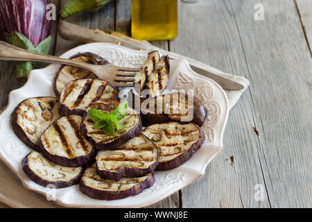 Gegrillte Auberginen gewürzt mit Olivenöl auf einem Holztisch Stockfoto