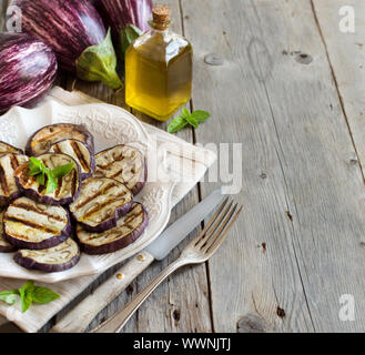 Gegrillte Auberginen gewürzt mit Olivenöl auf einem Holztisch Stockfoto