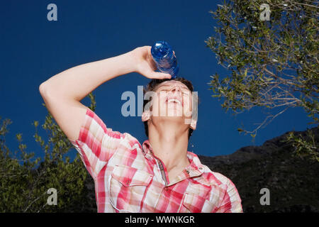 Junger Mann gießt Wasser über den Kopf Stockfoto