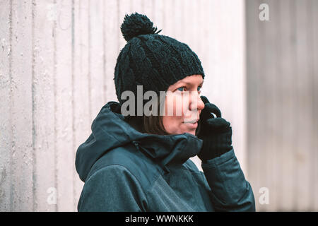 Ernsthafte Frau Gespräch am Handy draußen in der Kälte des Winters Tag Stockfoto
