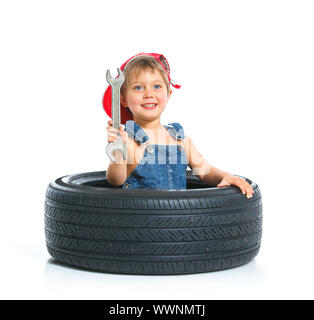 Süße kleine Mechaniker mit Reifen und Schraubenschlüssel Stockfoto