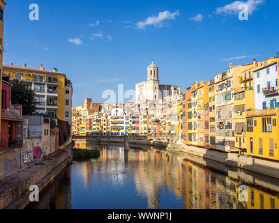 Von Girona typische Skyline Stadtbild über den Fluss Onyar Fluss mit bunten Häusern auf einem blauen sonnigen Himmel, die Kirche von Sant Feliu Kathedrale Wahrzeichen auf Ba Stockfoto