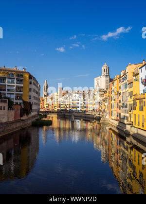 Von Girona typische Skyline Stadtbild über den Fluss Onyar Fluss mit bunten Häusern auf einem blauen sonnigen Himmel, die Kirche von Sant Feliu Kathedrale Wahrzeichen auf Ba Stockfoto