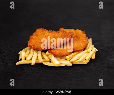 Panierte Deutsche Weiner Schnitzel mit Bratkartoffeln auf dunklem Hintergrund Stockfoto