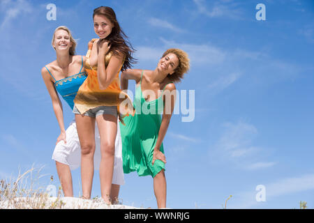 Drei weibliche Freunde Entspannung am Strand gegen den blauen Himmel Stockfoto