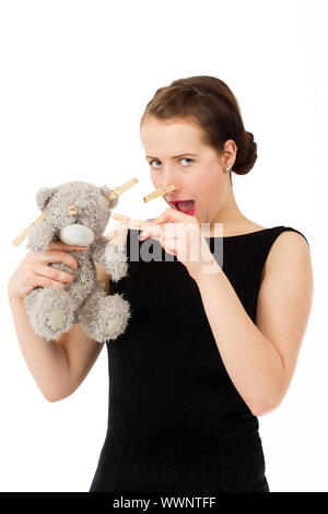 Attraktive smiling brunette Holding Teddybär Grimasse mit Peg auf der Nase Stockfoto