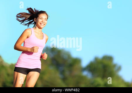 Glückliche Frau im City Park läuft. Asiatische Mädchen runner jogging Lächeln aspirational draußen auf schönen Sommertag. Mischlinge asiatische Chinesische/Kaukasisch Stockfoto