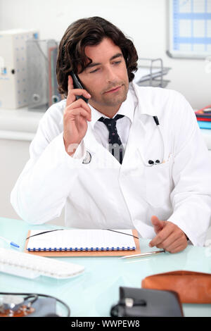 Arzt mit einem Telefon am Schreibtisch Stockfoto