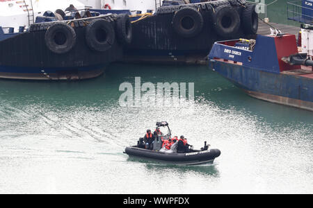 Eine Gruppe von Menschen gedacht, um Migranten werden zu Ufer durch Grenze Offiziere im Hafen von Dover, Kent nach einem kleinen Boot Vorfall im Kanal. Stockfoto