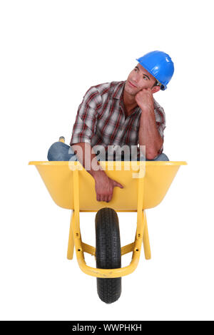 Verträumte Arbeiter sitzen in einer Schubkarre Stockfoto