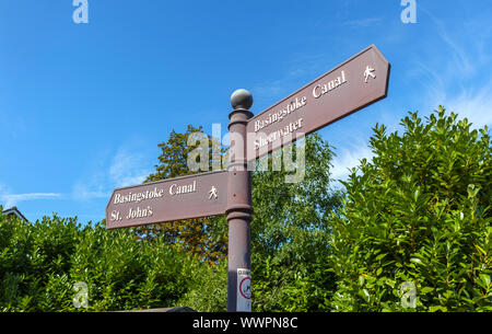 Wegweiser auf dem Leinpfad der Basingstoke Canal in Woking mit Wegbeschreibungen und nach der Nähe der Reiseziele Stockfoto