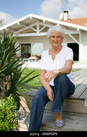 Ältere Dame saß auf Belag Stockfoto