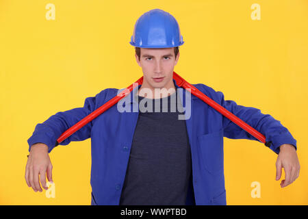 Handwerker mit einem riesigen Schraubenschlüssel hinter seinem Nacken Stockfoto