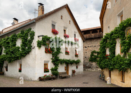 Eine sehr alte weiße Haus mit roten Blumen und Reben in Glurns (Südtirol, Italien) Stockfoto