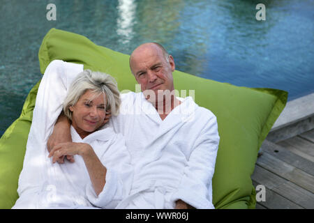 Älteres Ehepaar auf Luftmatratze auf einer Pool-Deck liegend Stockfoto