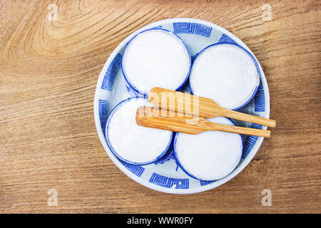 Thai Kokosmilch Pudding ist ein thailändisches Dessert aus Reismehl, Kokosmilch und Zucker der kleine Keramik Tassen sind auf einem Holzboden. Khano Stockfoto