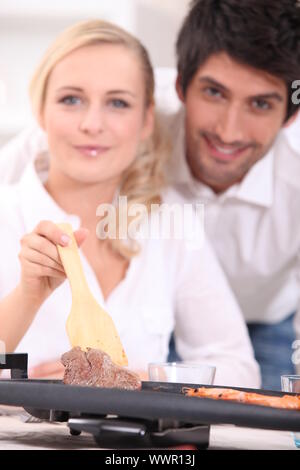 Junges Paar genießen ihr Abendessen auf einer Tischplatte Herdplatte Kochen Stockfoto