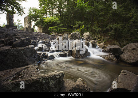 Lange Belichtung Bild eines Wasser über Felsen in einer Waldlandschaft fließt. Stockfoto