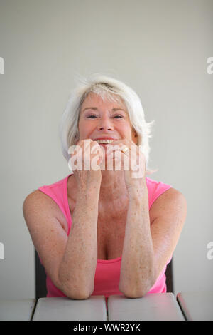 Reife Frau saß in dem Garten vor Lachen Stockfoto