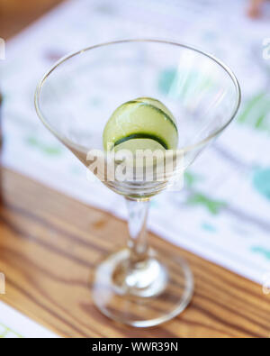 Leeren Martini Glas mit Gurke ice cube auf einen Tisch in einem Restaurant Stockfoto