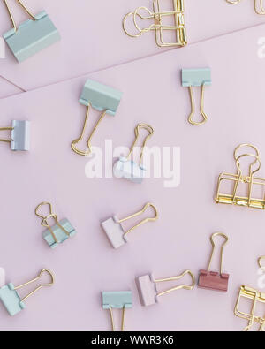 Mehrere pastellfarbenen binder clips liegen auf rosa Papier Stockfoto