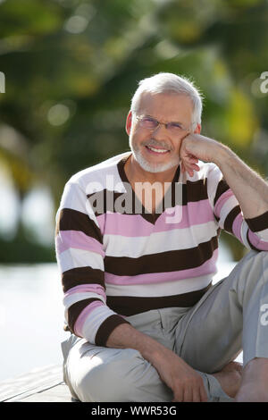 Älterer Mann saß im Garten Stockfoto