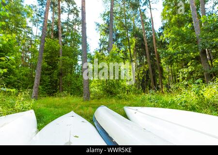 Sommer Wald Landschaft mit umgestürzten Kajaks liegen auf dem Boden. Landschaft mit Booten. Stockfoto