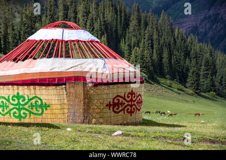 Fast fertige Kirgisischen Traditionelle Jurte Haus auf dem Hintergrund der Berge mit Nadelwald bedeckt. Kirgisistan Stockfoto