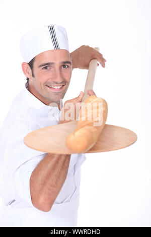 Bäcker ziehen ein frisch gebackenes Baguette aus dem Ofen Stockfoto
