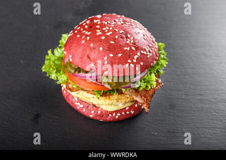 Red Burger mit Schnitzel und Gemüse auf einem Schneiden schiefer Board. Platz für Text Stockfoto