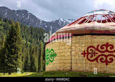 Fast fertige Kirgisischen Traditionelle Jurte Haus auf dem Hintergrund der Berge mit Nadelwald bedeckt. Kirgisistan Stockfoto