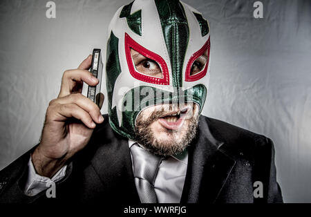 Ärger, wütend Geschäftsmann mit Maske des mexikanischen Kämpfer, gekleidet in Anzug und Krawatte Stockfoto