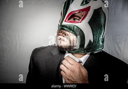 Arbeit, wütend Geschäftsmann mit Maske des mexikanischen Kämpfer, gekleidet in Anzug und Krawatte Stockfoto