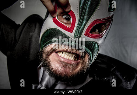 Wütend Geschäftsmann mit Maske des mexikanischen Kämpfer, gekleidet in Anzug und Krawatte Stockfoto