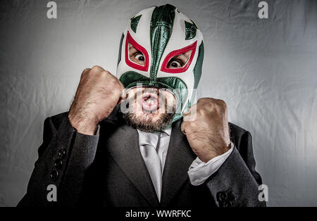 Stress, wütend Geschäftsmann mit Maske des mexikanischen Kämpfer, gekleidet in Anzug und Krawatte Stockfoto
