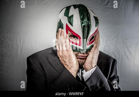 Stress, wütend Geschäftsmann mit Maske des mexikanischen Kämpfer, gekleidet in Anzug und Krawatte Stockfoto