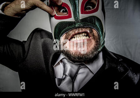 Wütend Geschäftsmann mit Maske des mexikanischen Kämpfer, gekleidet in Anzug und Krawatte Stockfoto