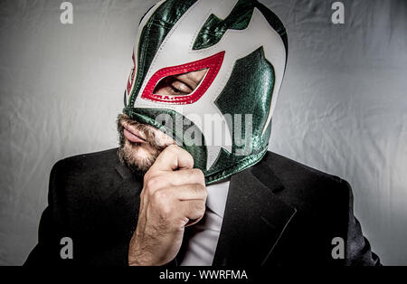 Wütend Geschäftsmann mit Maske des mexikanischen Kämpfer, gekleidet in Anzug und Krawatte Stockfoto