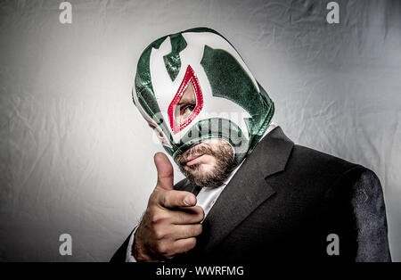 Chef, wütend Geschäftsmann mit Maske des mexikanischen Kämpfer, gekleidet in Anzug und Krawatte Stockfoto