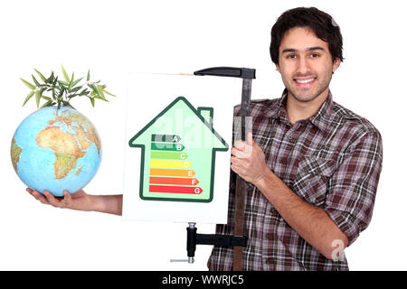 Handwerker, die eine Energie-Verbrauchs-Label und ein Globus mit grünen Pflanze festhalten Stockfoto
