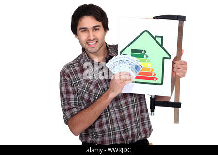 Mann, hält eine Energie-Verbrauchs-Label und eine Menge Geld in Bar Stockfoto