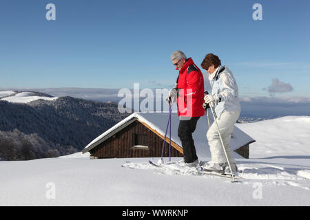 Ski paar vor chalet Stockfoto