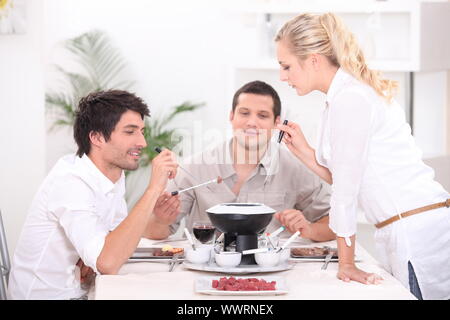 Drei Personen, Fondue Stockfoto