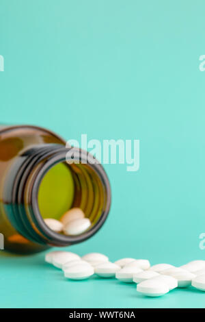 Weiße, runde Tabletten vor Glas Flasche Pillen verstreut Stockfoto