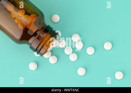 Weiße, runde Tabletten vor Glas Flasche Pillen verstreut Stockfoto