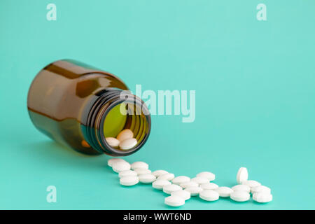 Weiße, runde Tabletten vor Glas Flasche Pillen verstreut Stockfoto
