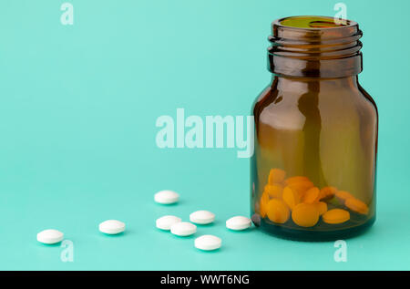 Weiße, runde Tabletten vor Glas Flasche Pillen verstreut Stockfoto