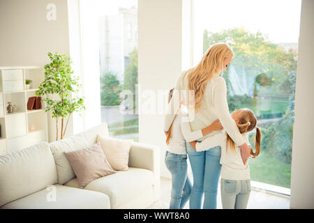 Hintere zurück hinter Blick auf Nizza stilvoll trendy schlanke Menschen Art Ausschreibung mama Mama mama Mädchen umarmt vor Fenster in modernen, hellen weißen Innenraum Stockfoto